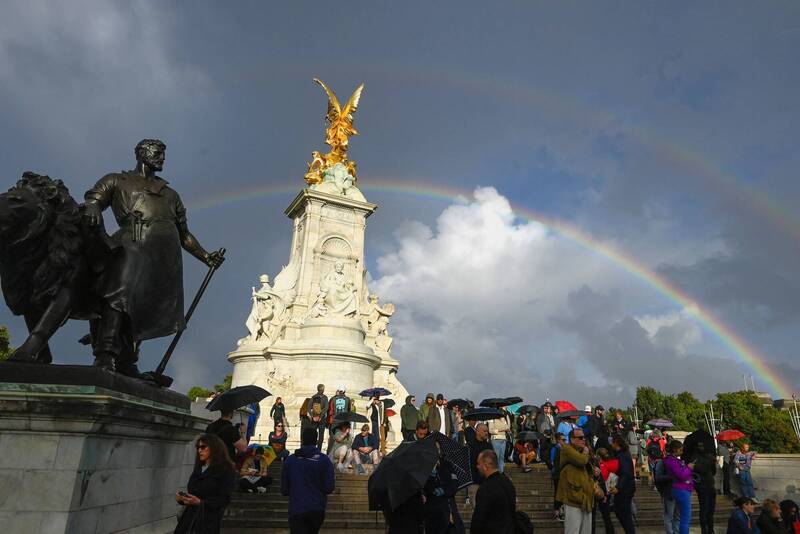 在女王離世前，大批民眾聚集在白金漢宮前，天空突然出現巨大虹霓。（路透）
