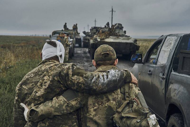俄罗斯今天表示，正对乌克兰前线各地发动「大规模空袭」。图为一名乌克兰士兵在收复的哈尔科夫领土上帮助一名受伤的战友。（美联社）(photo:LTN)