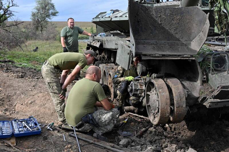 烏軍士兵取下俄軍戰車的可用零件。（法新社）