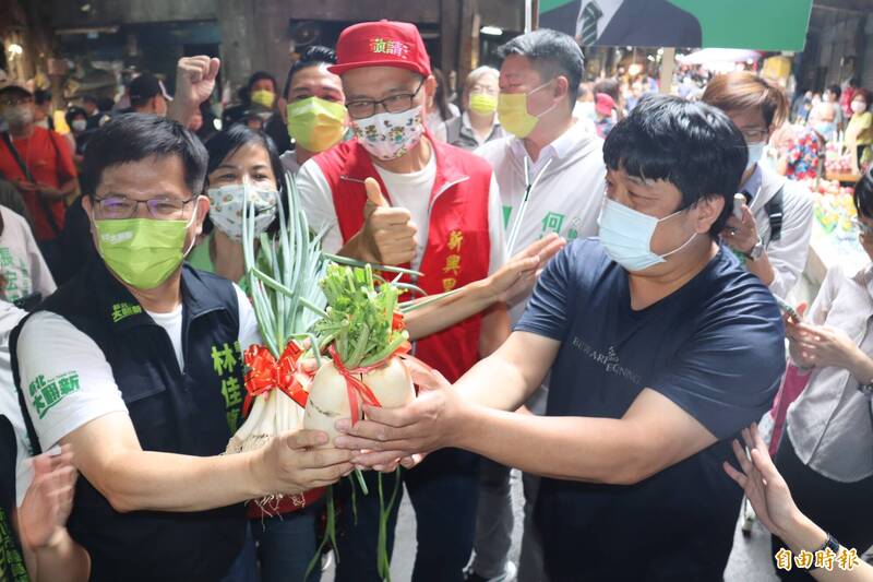 新北市長參選人林佳龍走入湳興市場，有攤商以「菜頭」相贈，祝高票當選。（記者翁聿煌攝）