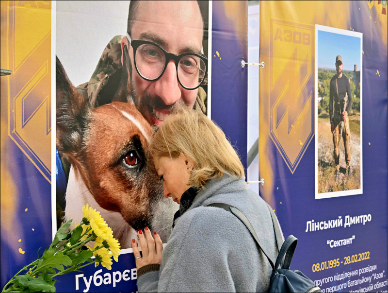 乌克兰十四日庆祝「卫士日」，基辅市中心举办「亚速营—马立波的天使」露天展览，展出死守马立波钢铁厂而战死的士兵生前身影。图为一名女子头靠在亲戚的照片上哀思。（法新社）(photo:LTN)