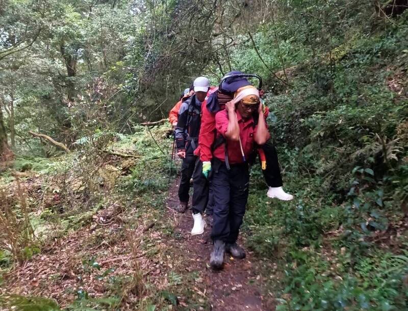 女山友登西巒大山途中遭蜈蚣咬傷，消防隊員背負到登山口送醫。（記者劉濱銓翻攝）