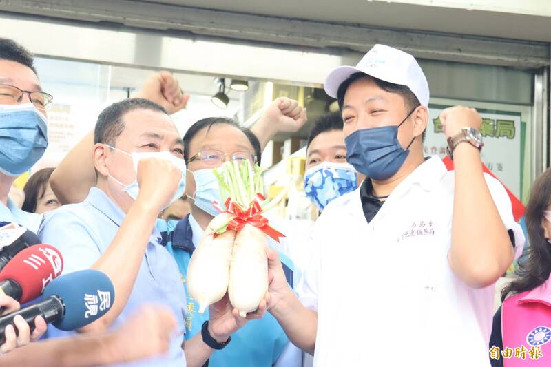 新北市長侯友宜走訪市場，攤商熱情相贈大蒜菜頭吉祥物。（記者翁聿煌攝）