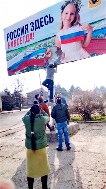 赫尔松市居民11日撕毁俄军一处巨型宣传看板。（路透）(photo:LTN)