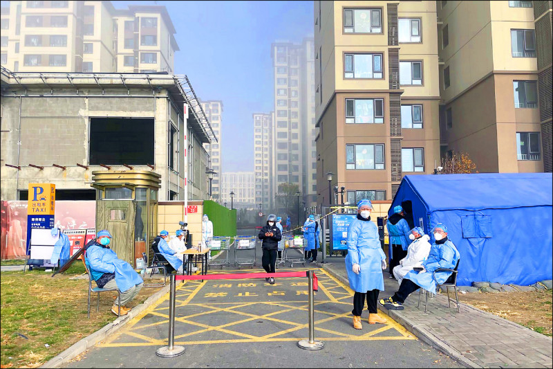 北京大興區一處社區25日由防疫工作人員守著進出口。（彭博）