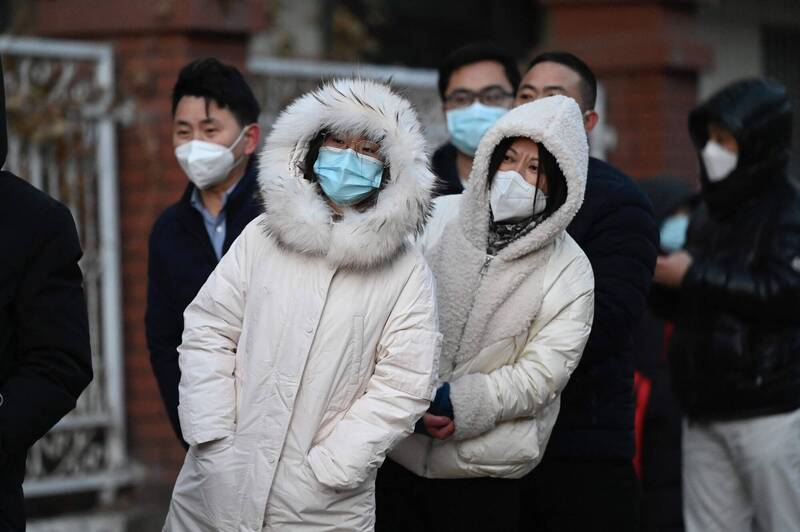 北京市民排队等着PCR採检，其中两名女性全身裹上厚重的冬衣御寒，忍不住探头看，似乎想知道等了半天的队伍到底有没有动静？（法新社）(photo:LTN)