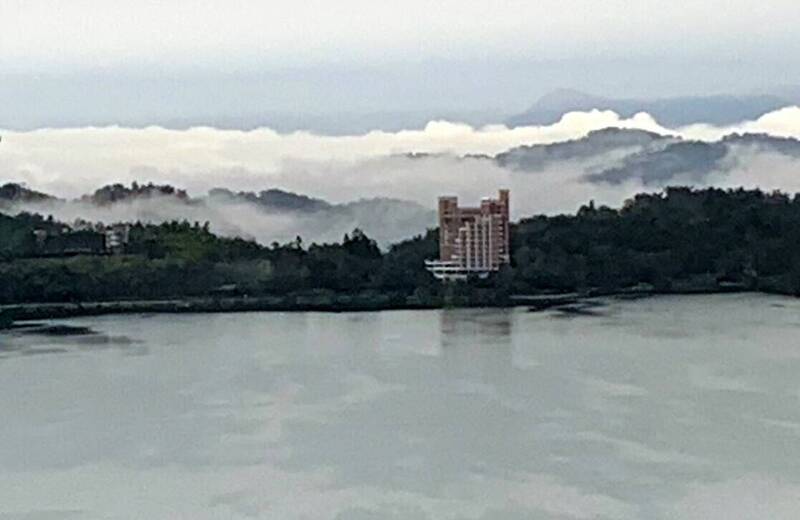 東北季風吹拂下，日月潭的潭水（前）與環湖的群峰、雲海（後）交織出如山水畫般美景。（圖由民眾提供）