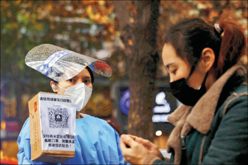 「健康码」是否会随着「通信行程卡」下线而退场，成为中国民众热议话题。健康码在中国各个城市有不同名称，在上海称为「随申码」，在北京市则为「健康宝」。图为北京防疫人员11月间在核酸检测地点，指引民众扫「健康宝」条码。（路透）(photo:LTN)