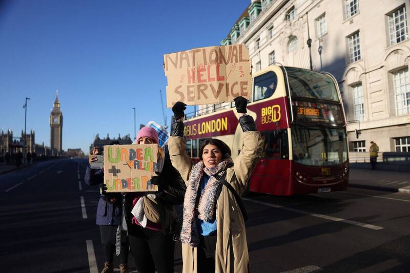 英国护理师大罢工，一名抗议者高举标语，讽刺主管机关国民健保署（National Health Service，NHS）。（彭博）(photo:LTN)