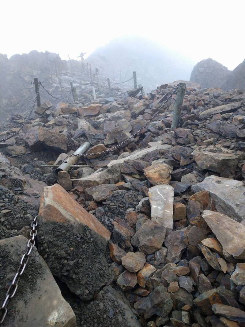 玉山主峰線風口路段鐵鍊柱被地震落石砸毀，玉管處派人上山搶修。（玉山國家公園管理處提供）