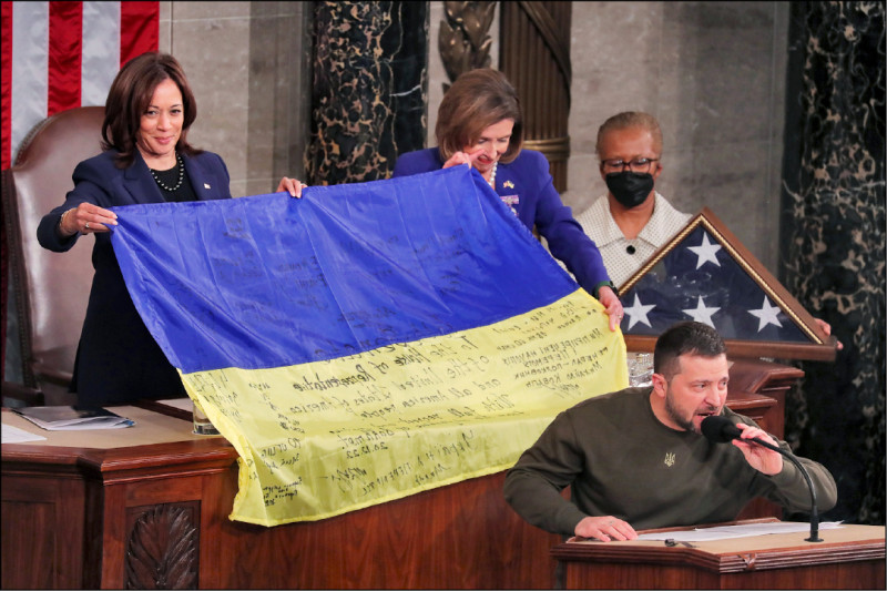 澤倫斯基對美國國會兩院聯席會議發表演說，將一面有戰爭前線巴赫姆特戰士簽名的烏克蘭國旗贈給美國副總統賀錦麗（左）與眾院議長裴洛西（左二）。（歐新社）