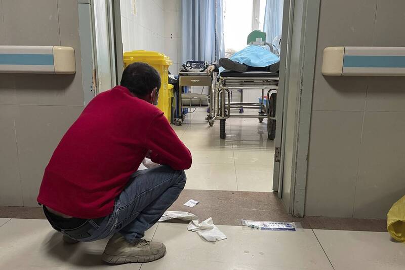 1名男子21日蹲在中国河北省涿州市的保定市第二中心医院的治疗室外，诊间内则有1名年长病患正在接受治疗。（美联社）(photo:LTN)