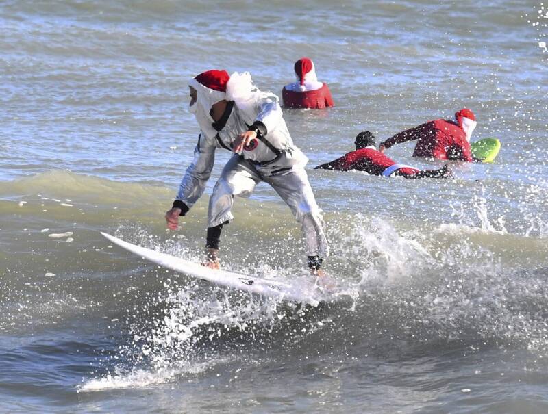 美国佛州陷入低温，仍出现上百名耶诞老人快乐冲浪，充满了节日的气息。（美联社）(photo:LTN)