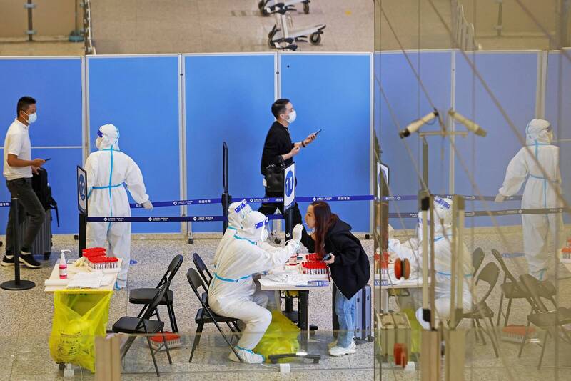 中国国家卫生健康委员会26日宣布，2023年1月8日取消入境人员全员核酸检测和集中隔离措施。图为上海虹桥机场医护人员为旅客进行PCR检测。（路透）(photo:LTN)