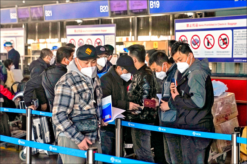 中国在疫情升温之际宣布放宽出入境管制，让各国拉警报。廿九日在北京首都国际机场，一批戴口罩的中国民众准备搭机出国。（美联社）(photo:LTN)