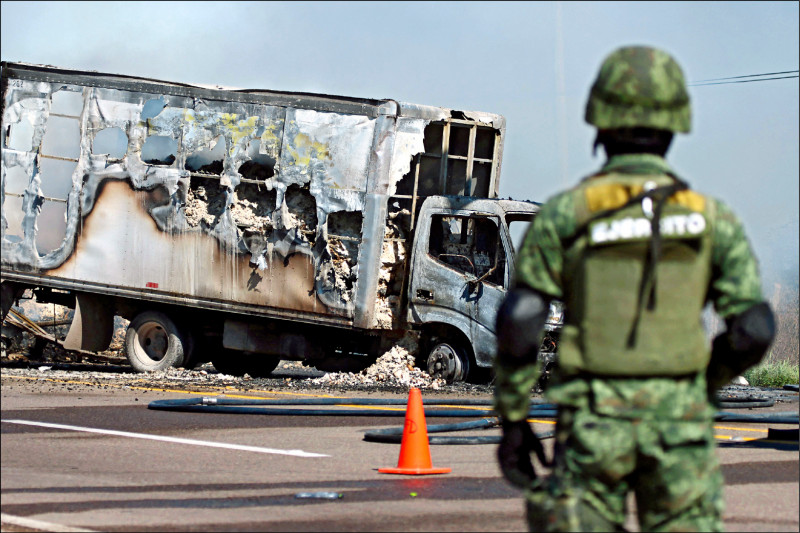 墨西哥販毒集團西納羅亞為阻止歐維迪歐被捕，在街上燒車擋路，一名墨國軍人持續在周遭戒備。（路透）