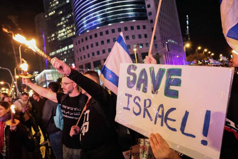 以色列人民14日晚間走上首都特拉維夫街頭，抗議總理納坦雅胡任內的司法改革，抨擊這是對民主政治的攻擊。（法新社）
