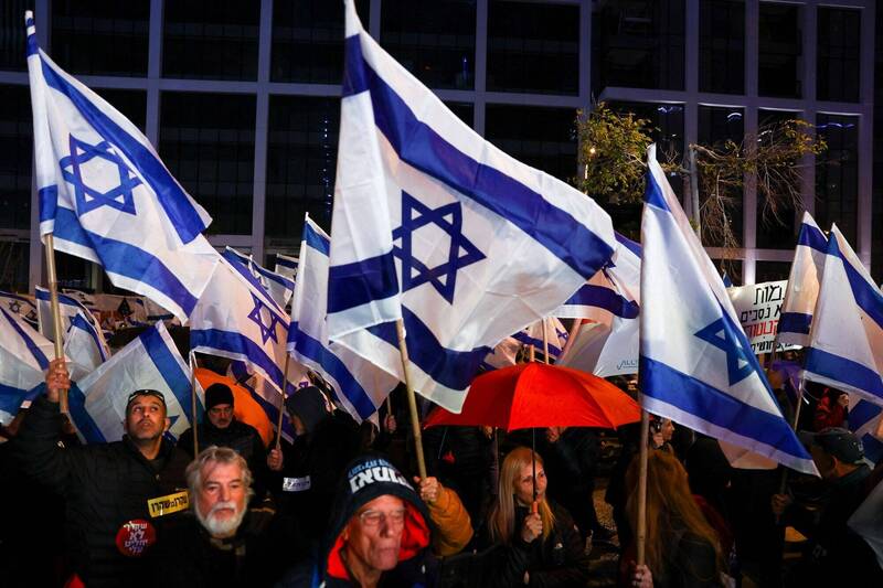 數萬名以色列民眾冒雨走上街頭，抗議納坦雅胡政府的司法改革計劃。（路透）