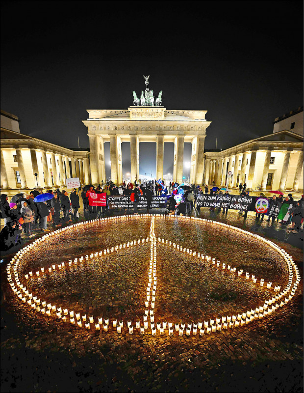 德國柏林知名地標布蘭登堡大門前，民眾以蠟燭排出和平符號，紀念烏俄開戰一週年。
（法新社）
