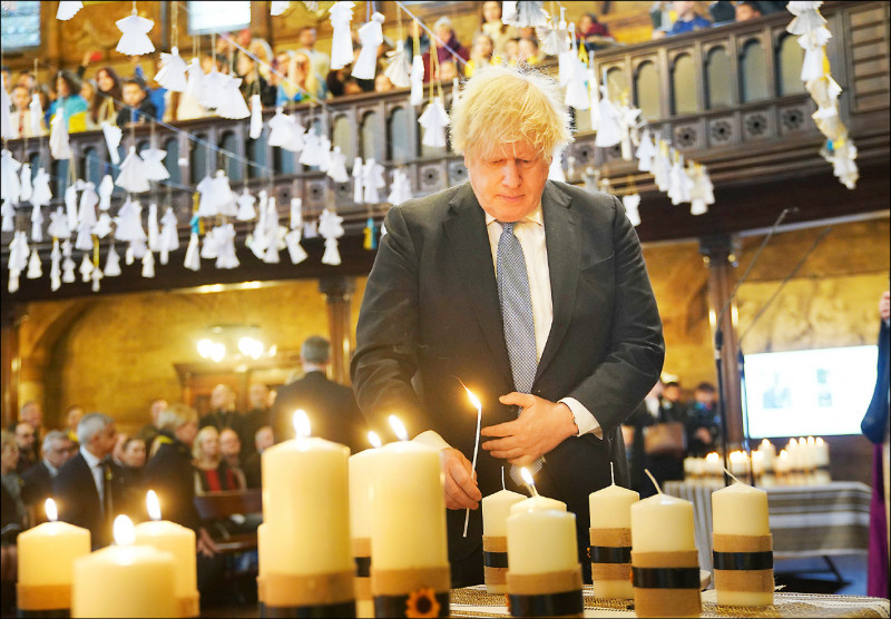 英國前首相強森在倫敦的烏克蘭天主教教堂點燃五十二根蠟燭，守護已英勇奮戰五十二週的烏克蘭。（美聯社）