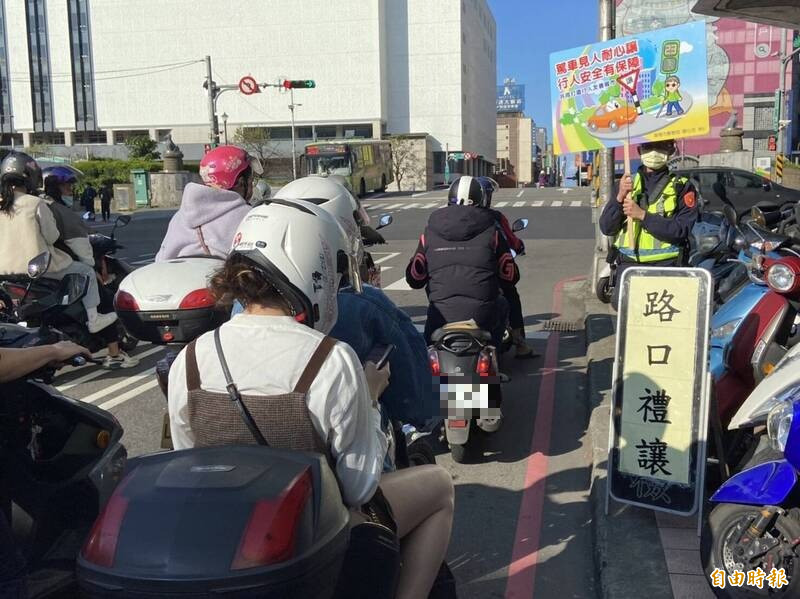 基隆市警局在路口舉牌宣導車輛禮讓行人。（記者盧賢秀攝）