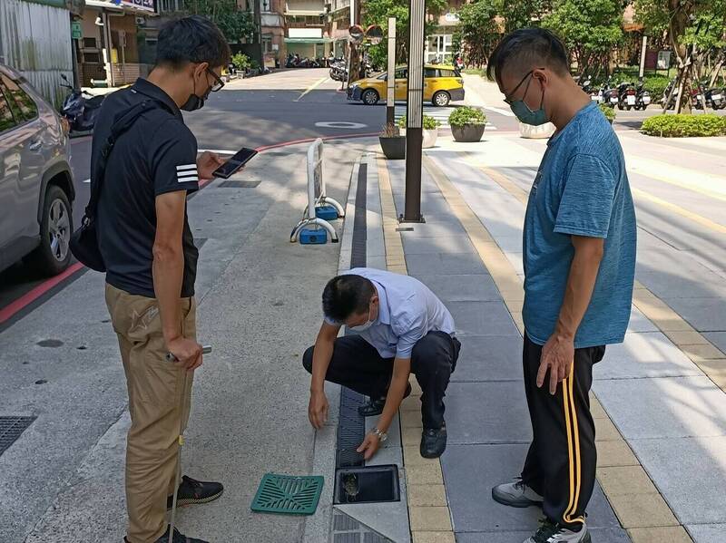 新北市政府水利局將展開透水保水設施抽查，圖為技師開啟格柵板，檢查內部有無淤積堵塞，以確保基地周邊截水溝排水無虞。（圖由新北市水利局提供）