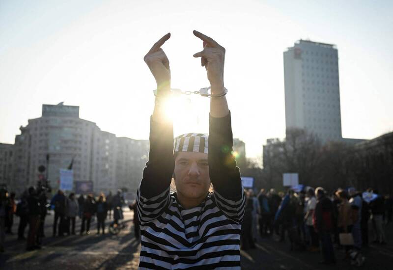 羅馬尼亞布加勒斯特4日一場示威活動上，示威者舉出比中指的手勢。（法新社）