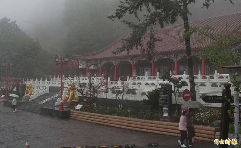 梨山地區降雨，遊客撐傘在梨山賓館前參觀。（記者張軒哲攝）