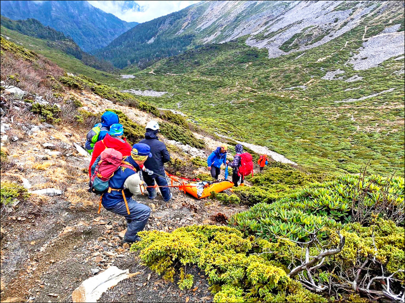 救難人員以人力搬運方式，將攀登雪山、高山症發作身亡的曹姓義消遺體運送下山。（苗栗縣消防局提供）