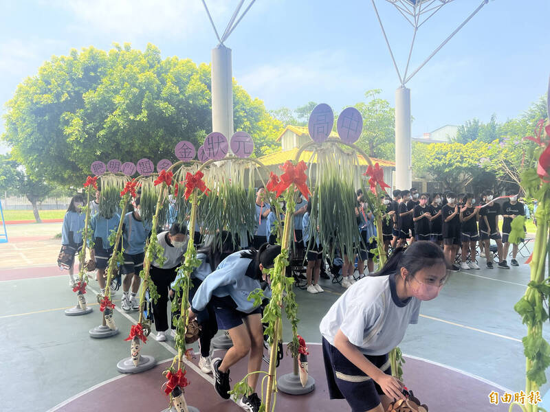 國三考生依序走過用蔥、芹菜和菜頭打造的「成功門」。（記者林旻臻攝）