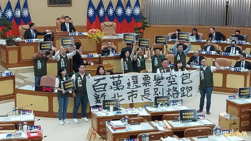 新北市民進黨議員在備詢台前拉白布條，高喊口號要新北市長侯友宜「百萬選票變空包，新北市長別烙（落）跑」。（記者許倬勛攝）