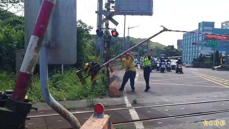 台鐵深澳支線基隆和瑞芳交界處電路不良，平交道遮斷桿無法升起，只好以人力抬起遮斷器。（記者盧賢秀攝）