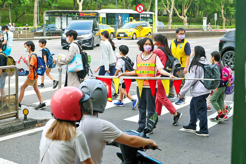 A crossing guard helps children cross the street in Taipei’s Daan District yesterday. 
Photo: CNA