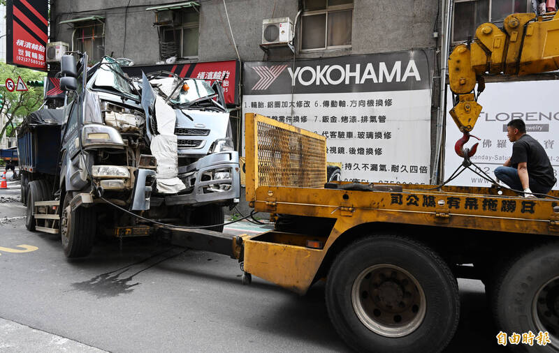 台北市信義區松德路120號18日清晨發生砂石車撞進民宅案，因車子撞擊承重柱，北市府擔心若貿然移車，恐導致整間房子有傾倒之虞，經由工程人員在店家騎樓架設3支承重鋼柱後，拖吊車終於將肇事砂石車車體拖出。（記者廖振輝攝）