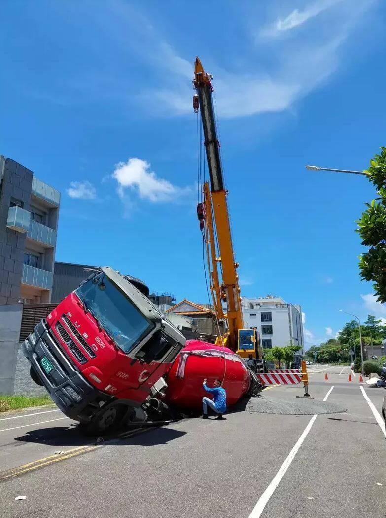 南市安平區府平路突然出現坑洞，一輛預拌混凝土車陷傾斜，台南市府獲報派員趕往以大吊車拖吊。（南市工務局提供）