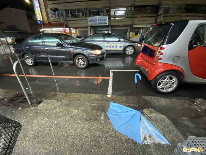 肇事車輛（左）撞倒婦人，傷者送醫後留下破損藍色雨傘。（記者黃旭磊攝）