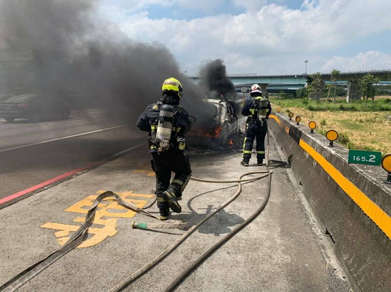 一輛休旅車在國道一號神岡路段起火燃燒，消防人員前往灌救。（民眾提供）