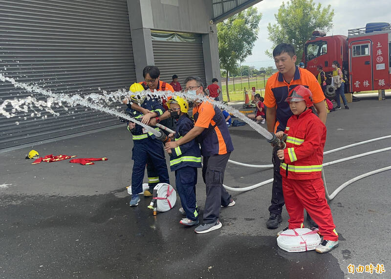 小朋友穿上消防員裝備，體驗消防員射水滅火過程。（記者林旻臻攝）