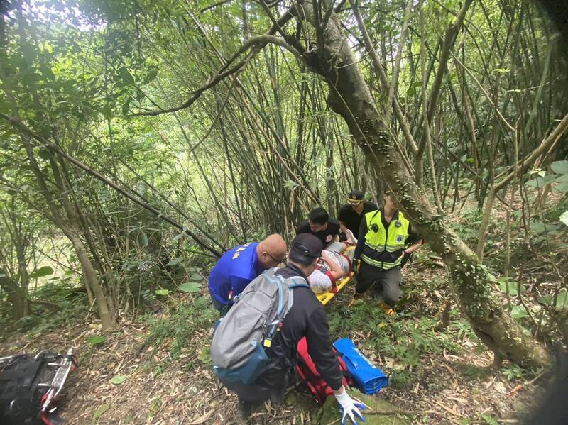 林姓老婦人滑落山坡，消防隊員利用長背板將其固定後，送往醫院救治。（記者吳昇儒翻攝）