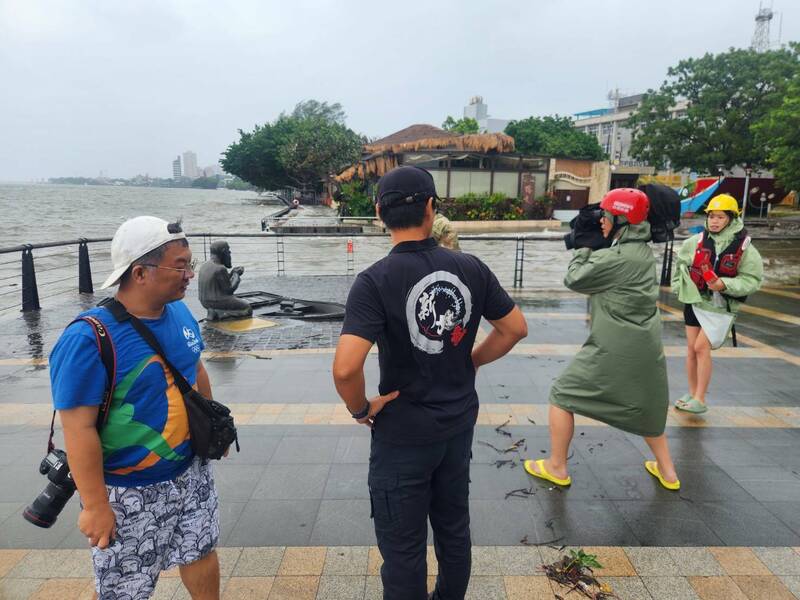 卡努颱風襲台，適逢今天大潮，淡水河水勢淹上步道，馬偕上岸處雕像再遭水淹，新北消防局淡水中隊前往勸離民眾，拉起封鎖線。（記者吳仁捷翻攝）