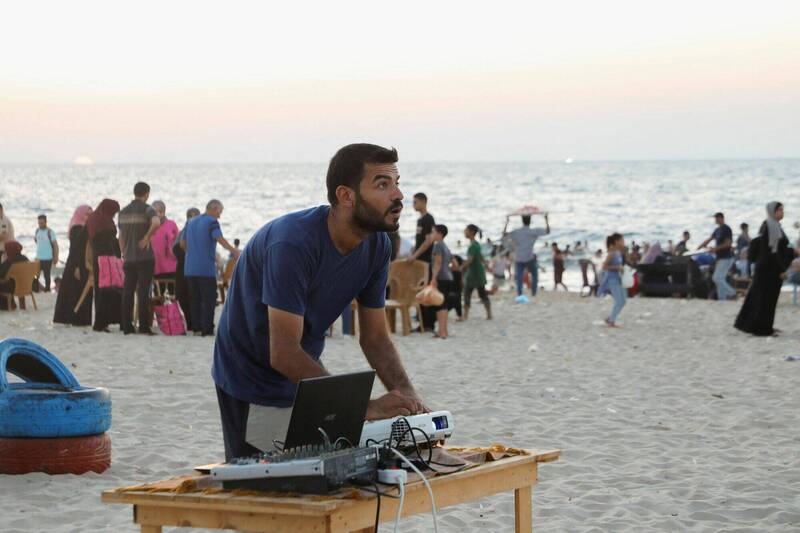 2023年7月28日，1名巴勒斯坦男子在加萨市1处沙滩调整投影机，为稍后登场的沙滩露天电影院做准备。（路透）(photo:LTN)