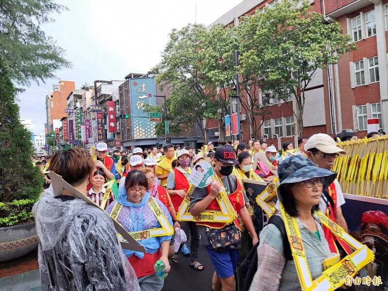 農曆鬼門開，新竹市竹塹中元城隍祭「夯枷解厄」登場，信眾細雨中負枷前行。 （記者洪美秀攝）