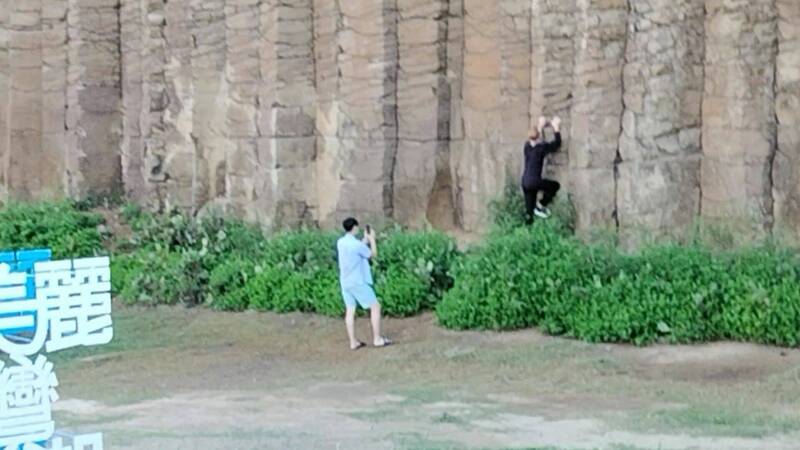 外國女子攀爬西嶼大菓葉玄武岩柱，旁邊友人協助拍照。（記者劉禹慶翻攝）