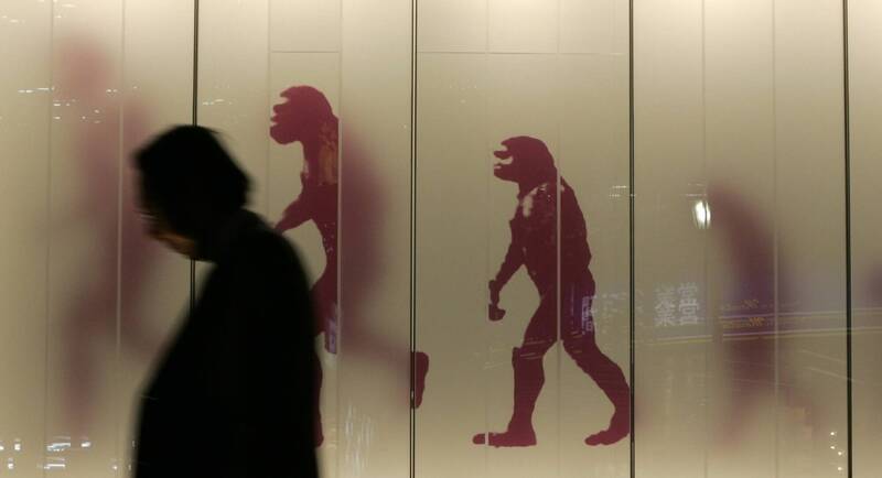东京街头一名路人走过一幅人类演化图样前。（路透档案照）(photo:LTN)