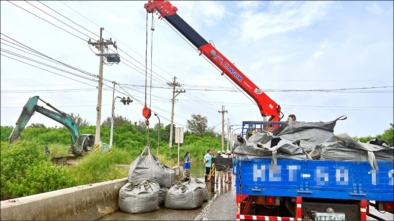 萡子寮漁港昨日上午海水倒灌，福安橋堆置砂包阻擋海水蔓延至下崙村。（記者林旻臻攝）