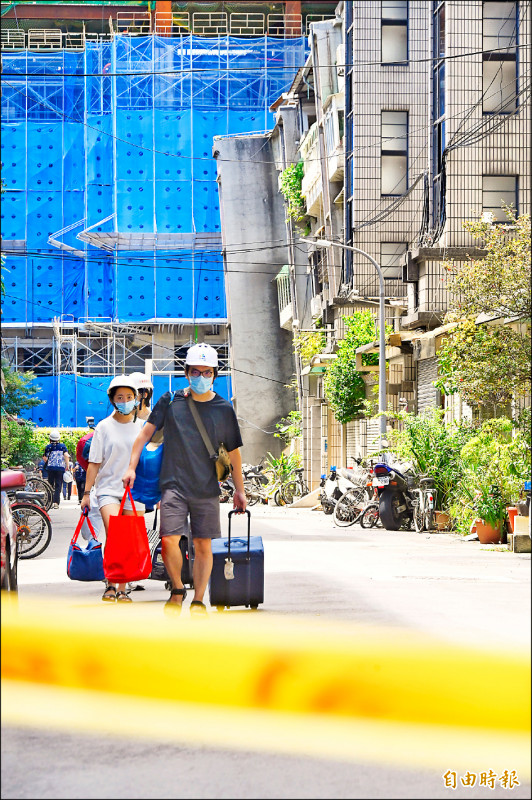 住戶戴安全帽返家收拾行李。（記者劉信德攝）