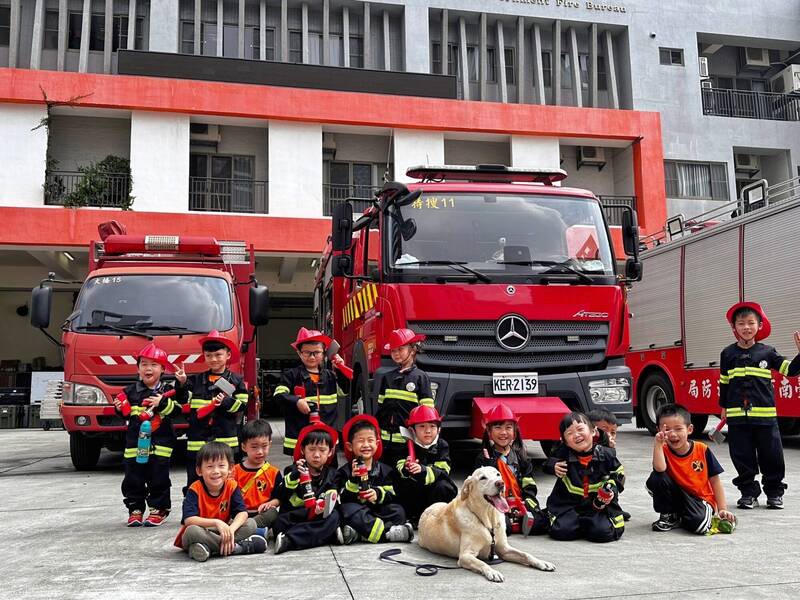 幼兒園小朋友參觀台南市消防局特搜大隊大橋特搜分隊，穿上小小消防衣，開心與搜救犬互動合影。（圖由大橋特搜分隊提供）