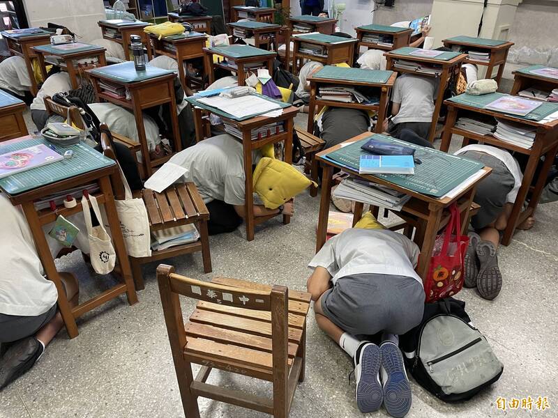 地震模擬通報，學生們躲在書桌下方保護頭部。（記者許智翔攝）