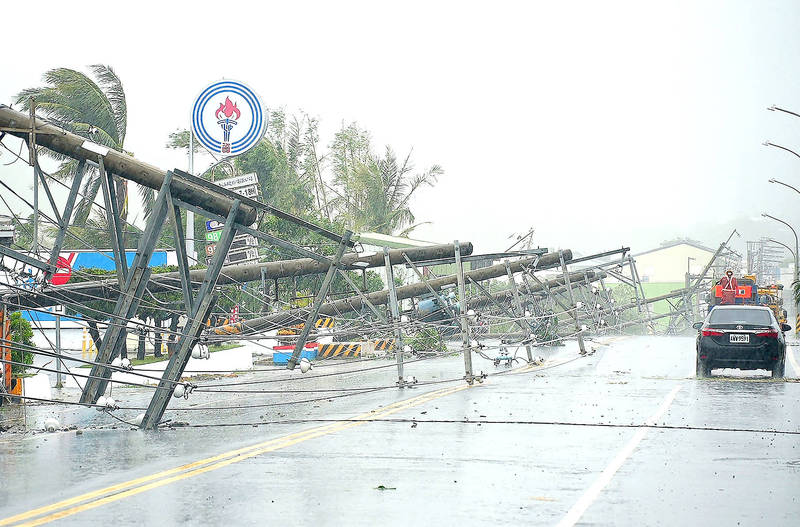 A car passes by power lines downed by the high winds from Typhoon Koinu in Pingtung County yesterday.
Photo: Sean CHANG, AFP