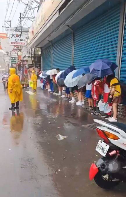 有網友分享影片，指桃園的學生淋著雨上學，畫面中可看到一整排學生擠在店家屋簷下撐傘躲雨，網友砲轟張善政「你現在依然在被窩裡面，但小朋友並沒有，桃園市民也沒有。到底為什麼不好好把事情做好？」（圖擷自臉書）
